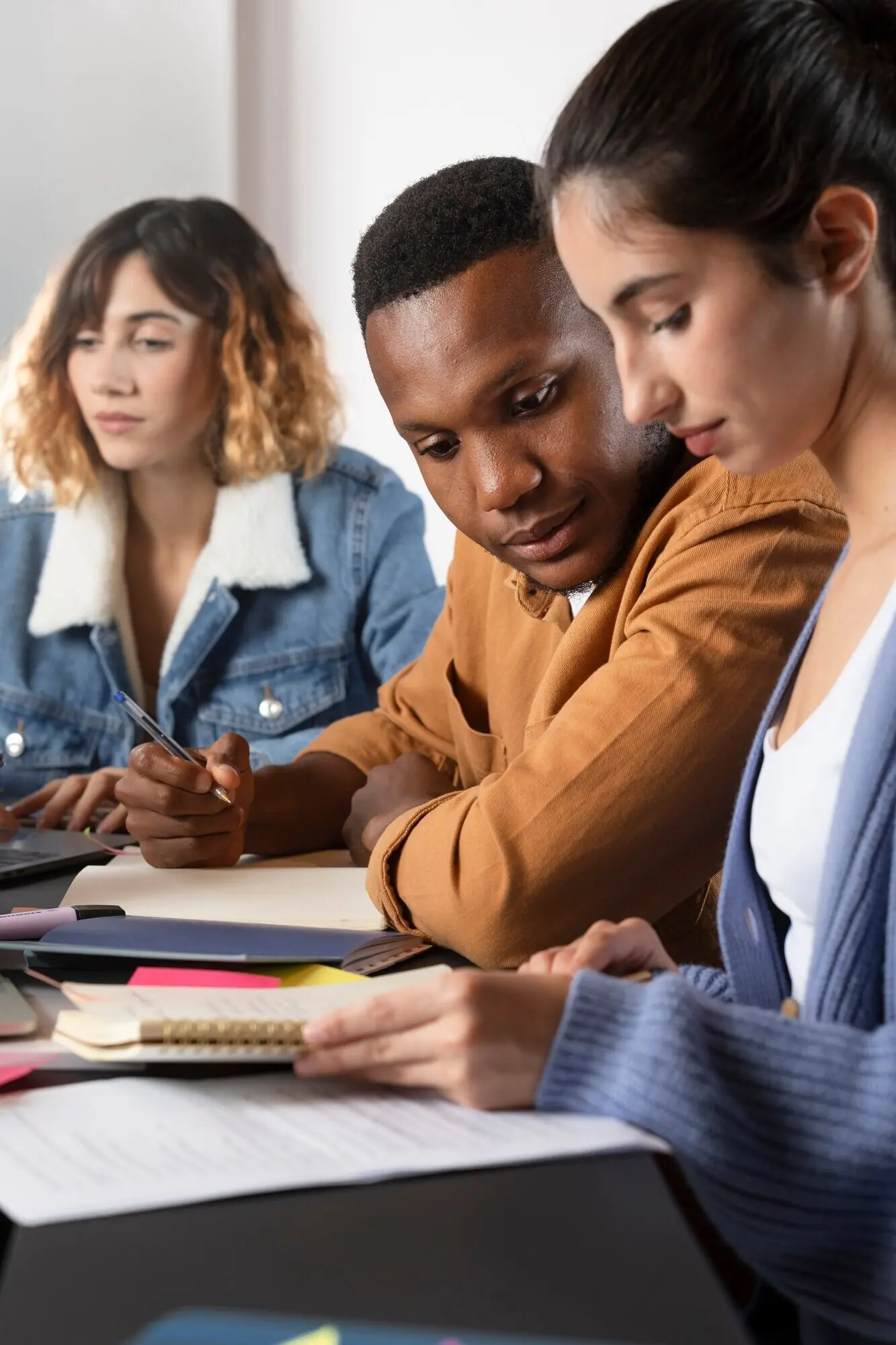 Junge Frau, die einer befreundeten Person etwas in einem Notizbuch zeigt.